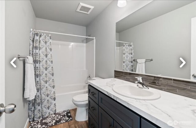 bathroom with visible vents, toilet, wood finished floors, shower / bathtub combination with curtain, and vanity