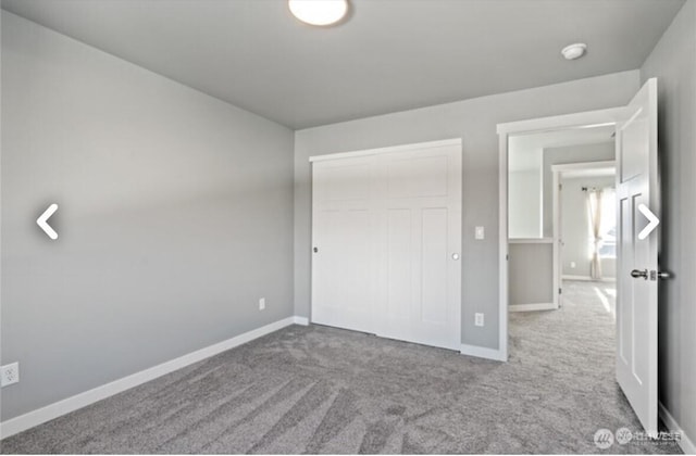 unfurnished bedroom with carpet, a closet, and baseboards