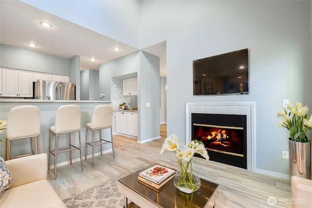 living room featuring recessed lighting, light wood-style flooring, baseboards, and a tile fireplace