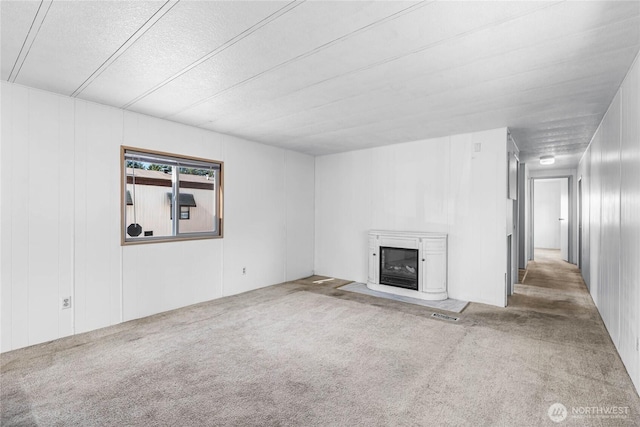 unfurnished living room featuring visible vents, carpet flooring, and a glass covered fireplace