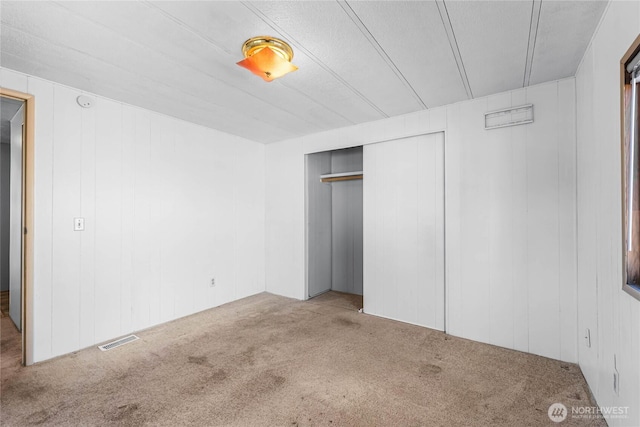 unfurnished bedroom with a closet, carpet flooring, and visible vents