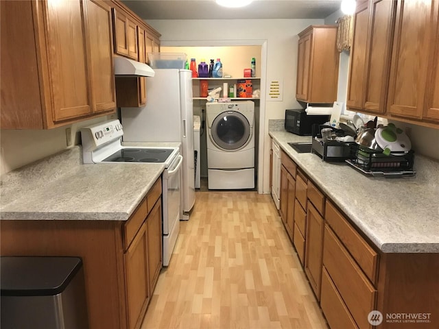 kitchen featuring brown cabinets, electric range, washer / dryer, black microwave, and under cabinet range hood