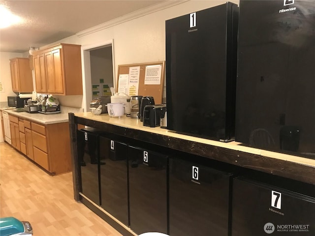 kitchen with black microwave, light wood-style floors, light countertops, light brown cabinetry, and crown molding