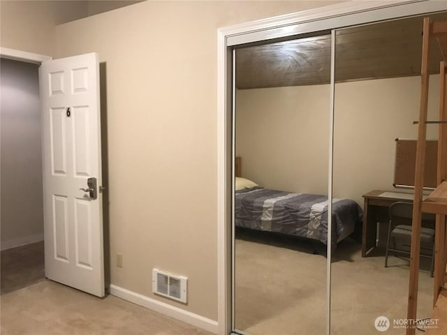 bedroom featuring a closet, visible vents, light carpet, and baseboards