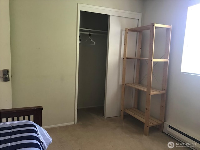 carpeted bedroom with a baseboard heating unit and a closet