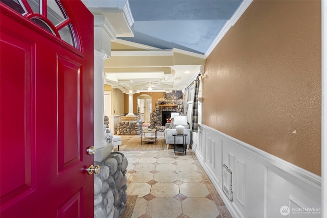 entryway with coffered ceiling, wainscoting, crown molding, ornate columns, and a fireplace