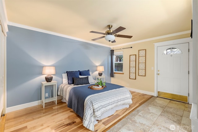 bedroom with a barn door, baseboards, a ceiling fan, ornamental molding, and wood finished floors