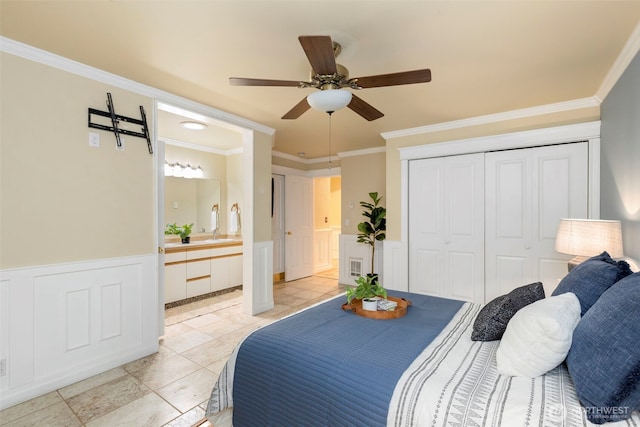 bedroom featuring a decorative wall, a wainscoted wall, a sink, ornamental molding, and a closet