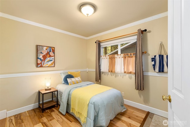 bedroom with crown molding, wood finished floors, and baseboards