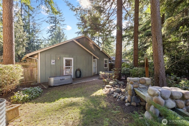 back of property featuring board and batten siding, a yard, fence, and a deck