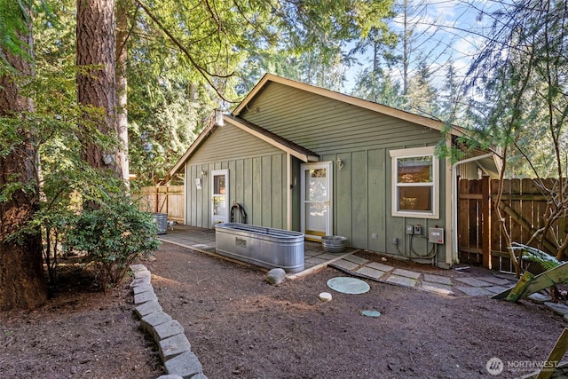 rear view of property with a patio, board and batten siding, and fence