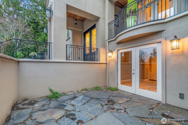 property entrance with stucco siding, a patio area, fence, and french doors