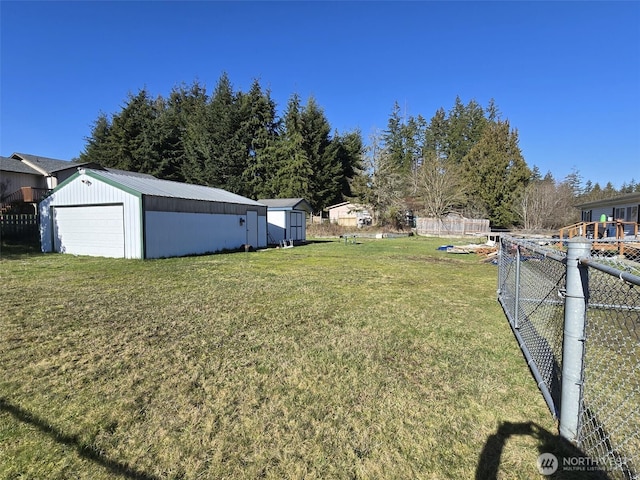 view of yard with a garage, an outdoor structure, and fence