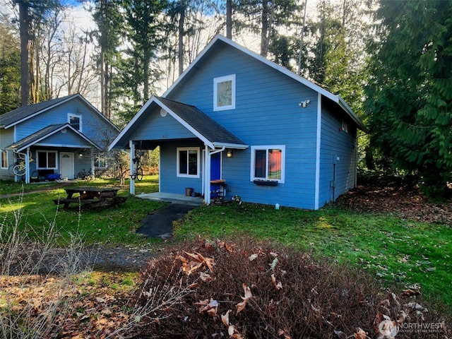 view of front of house with a shingled roof and a front lawn