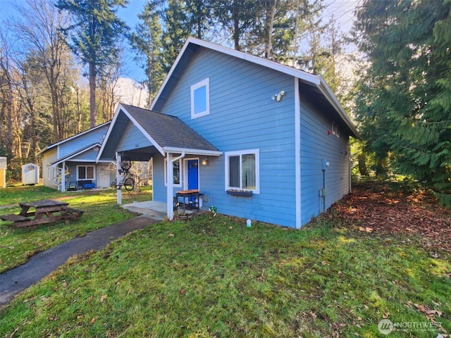 view of front of house with a shingled roof and a front yard