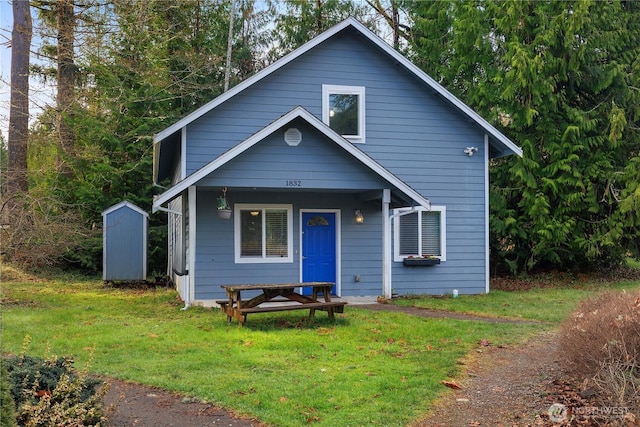 bungalow-style home with an outbuilding, a front lawn, and a storage unit