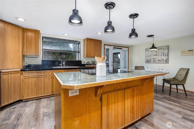 kitchen with tile countertops, a kitchen island, a sink, and wood finished floors