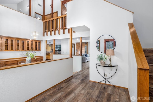 interior space featuring brown cabinets, dark wood finished floors, glass insert cabinets, a chandelier, and baseboards