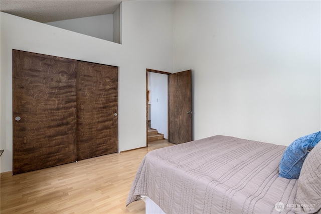 bedroom with high vaulted ceiling and light wood-style flooring