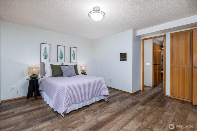 bedroom with dark wood-style floors, a textured ceiling, and baseboards