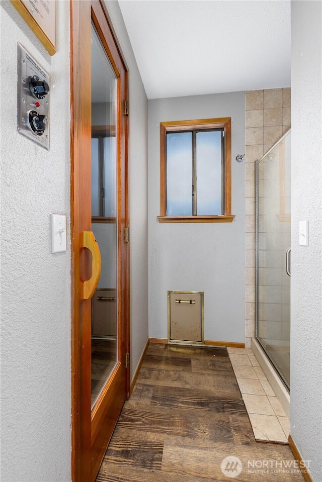 bathroom featuring a shower stall, baseboards, and wood finished floors