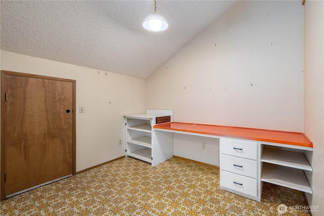 unfurnished office featuring lofted ceiling, built in study area, a textured ceiling, and baseboards