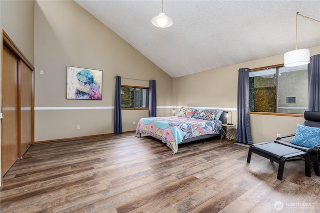 bedroom with high vaulted ceiling, a textured ceiling, baseboards, and wood finished floors