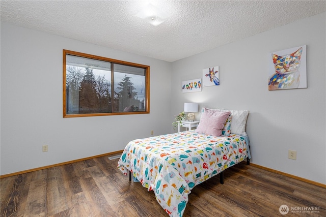 bedroom featuring a textured ceiling, baseboards, and wood finished floors