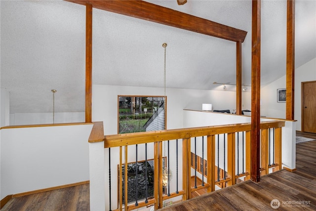 corridor featuring lofted ceiling with beams, a textured ceiling, baseboards, and wood finished floors