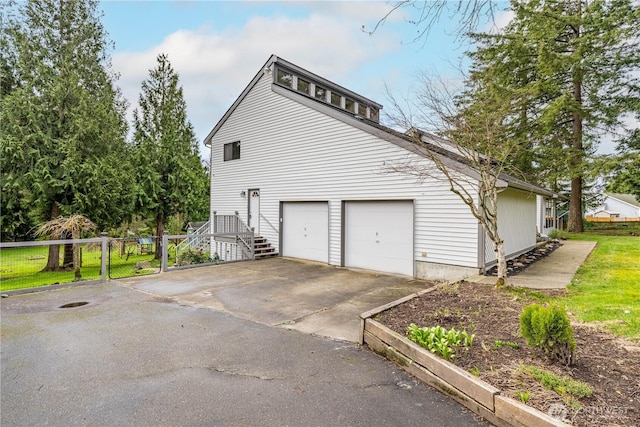 view of home's exterior with a garage, driveway, and fence