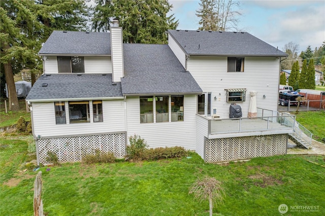 back of property featuring roof with shingles, a lawn, a chimney, and a wooden deck