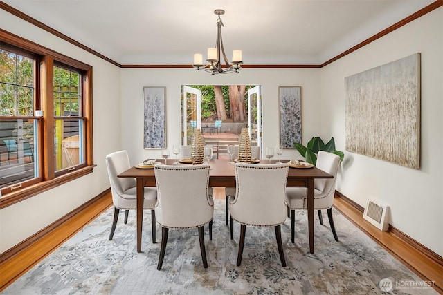 dining room with crown molding, a notable chandelier, wood finished floors, and visible vents