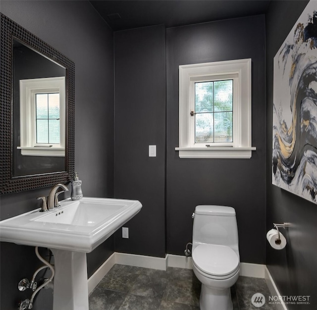 bathroom featuring a sink, baseboards, and toilet