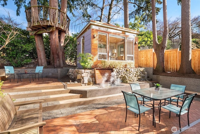 view of patio with outdoor dining space, an outdoor structure, and fence