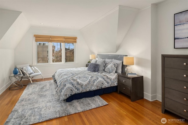 bedroom with vaulted ceiling, ornamental molding, baseboards, and wood finished floors