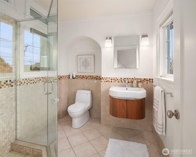 full bathroom with a shower stall, crown molding, toilet, tile patterned floors, and tile walls