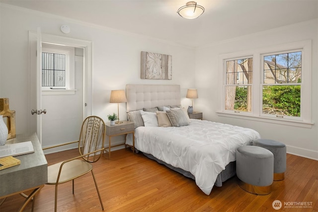 bedroom featuring baseboards, multiple windows, and light wood finished floors