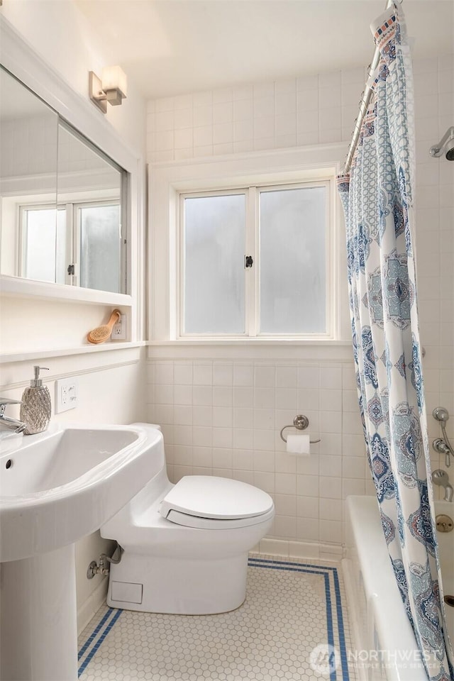 full bathroom with tile patterned floors, shower / bathtub combination with curtain, toilet, and tile walls