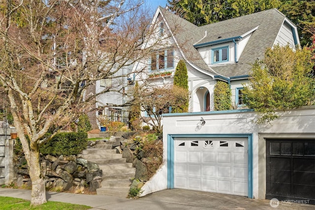 view of front of house featuring stairway, stucco siding, and a shingled roof