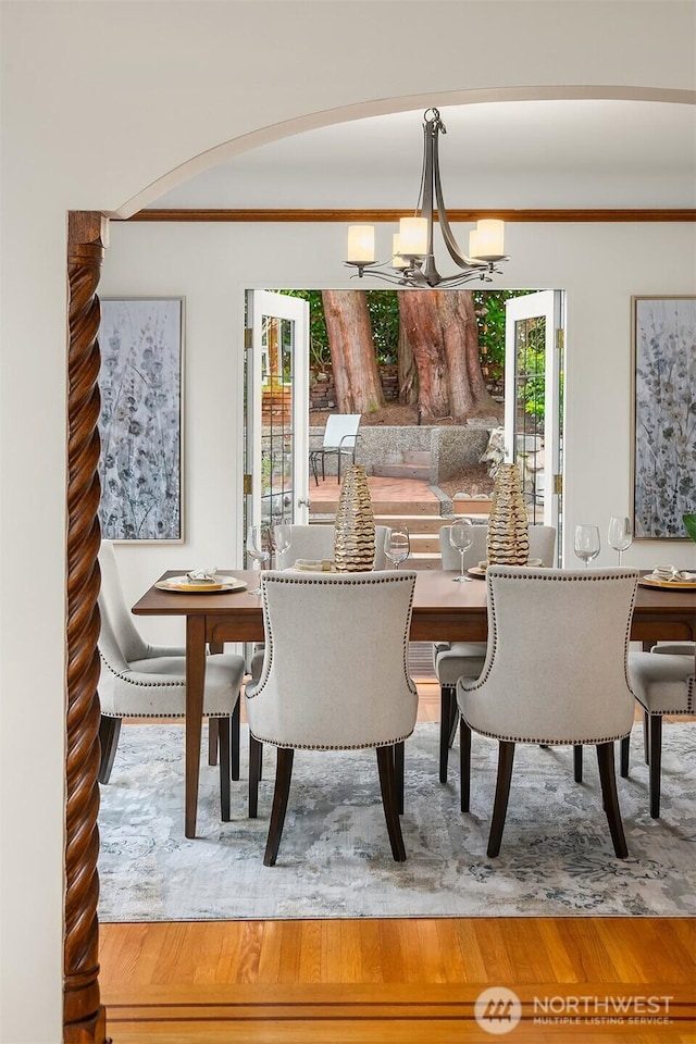 dining room featuring an inviting chandelier, crown molding, wood finished floors, and arched walkways