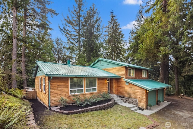 view of front of house with metal roof, driveway, a front yard, and an attached garage