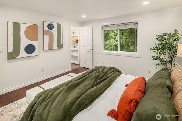 bedroom featuring recessed lighting, wood finished floors, baseboards, and ornamental molding