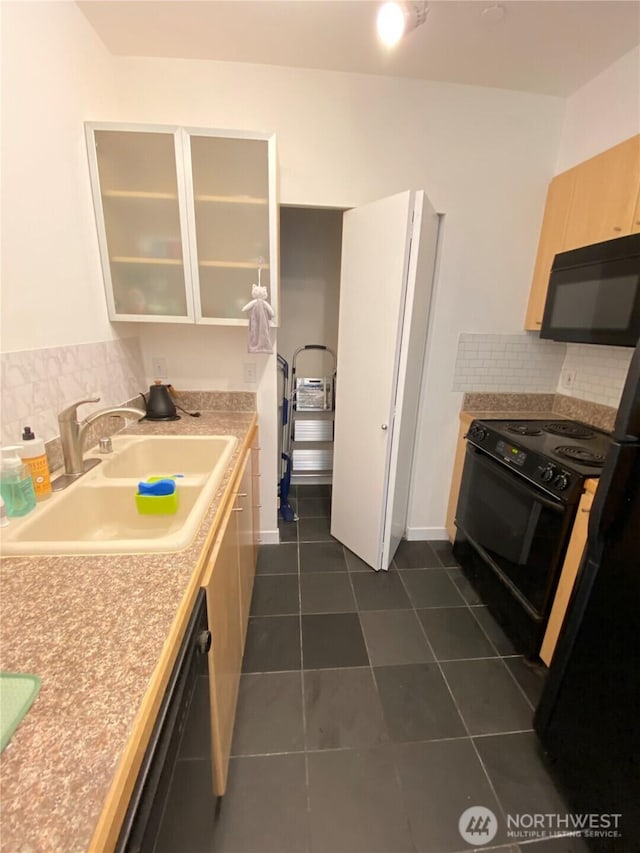 kitchen with a sink, light countertops, backsplash, black appliances, and glass insert cabinets