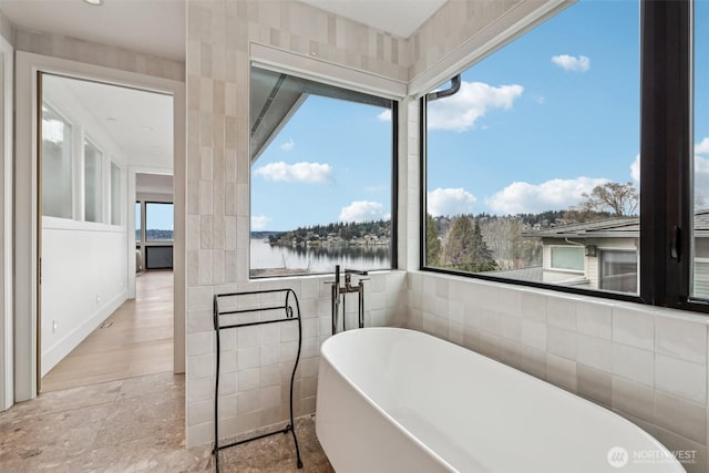 1658 10th St W, Kirkland, WA 98033 - full bathroom featuring a freestanding bath, a water view, tile walls, and stone finish flooring