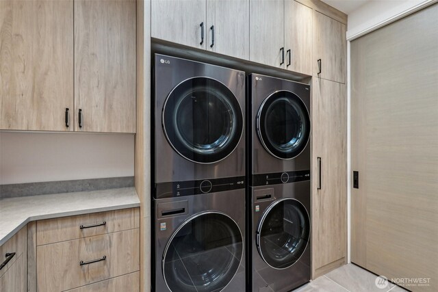 1658 10th St W, Kirkland, WA 98033 - washroom with cabinet space, stacked washer and clothes dryer, washer and clothes dryer, and light tile patterned floors
