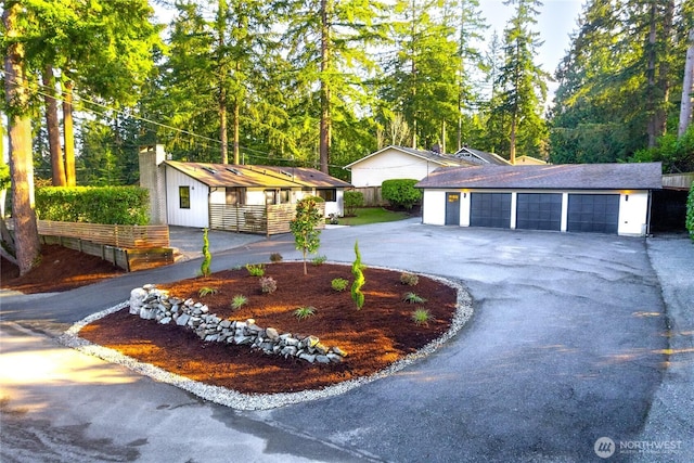 view of front of property featuring aphalt driveway, a garage, and an outdoor structure