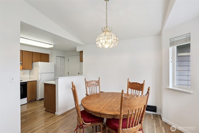 dining room featuring vaulted ceiling, light wood finished floors, and baseboards