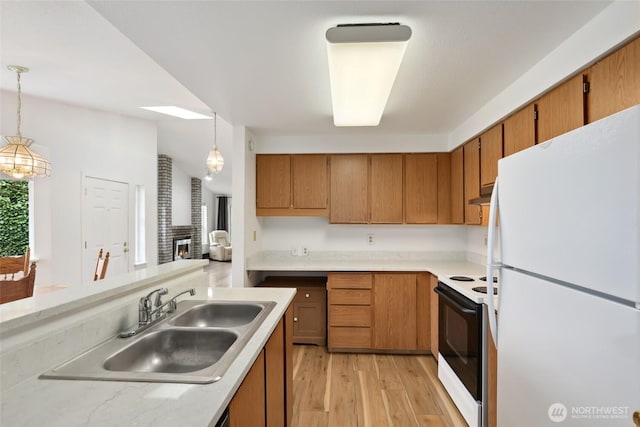 kitchen featuring light countertops, electric range oven, freestanding refrigerator, a sink, and under cabinet range hood