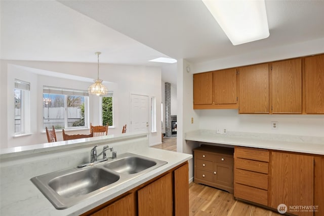 kitchen with brown cabinets, pendant lighting, light countertops, and a sink