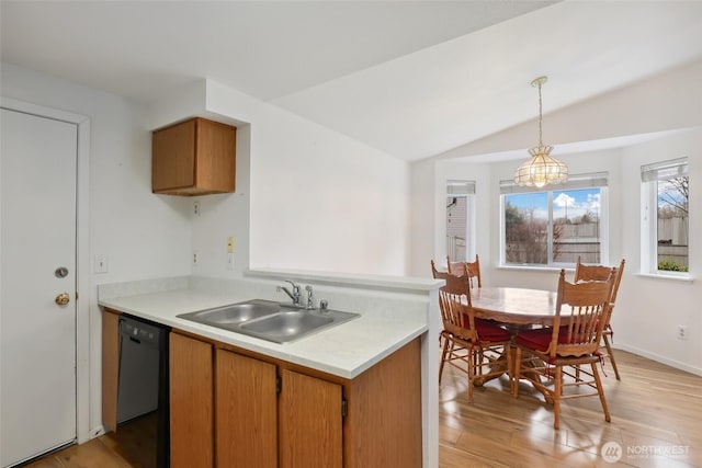 kitchen featuring light countertops, vaulted ceiling, a sink, light wood-type flooring, and dishwasher